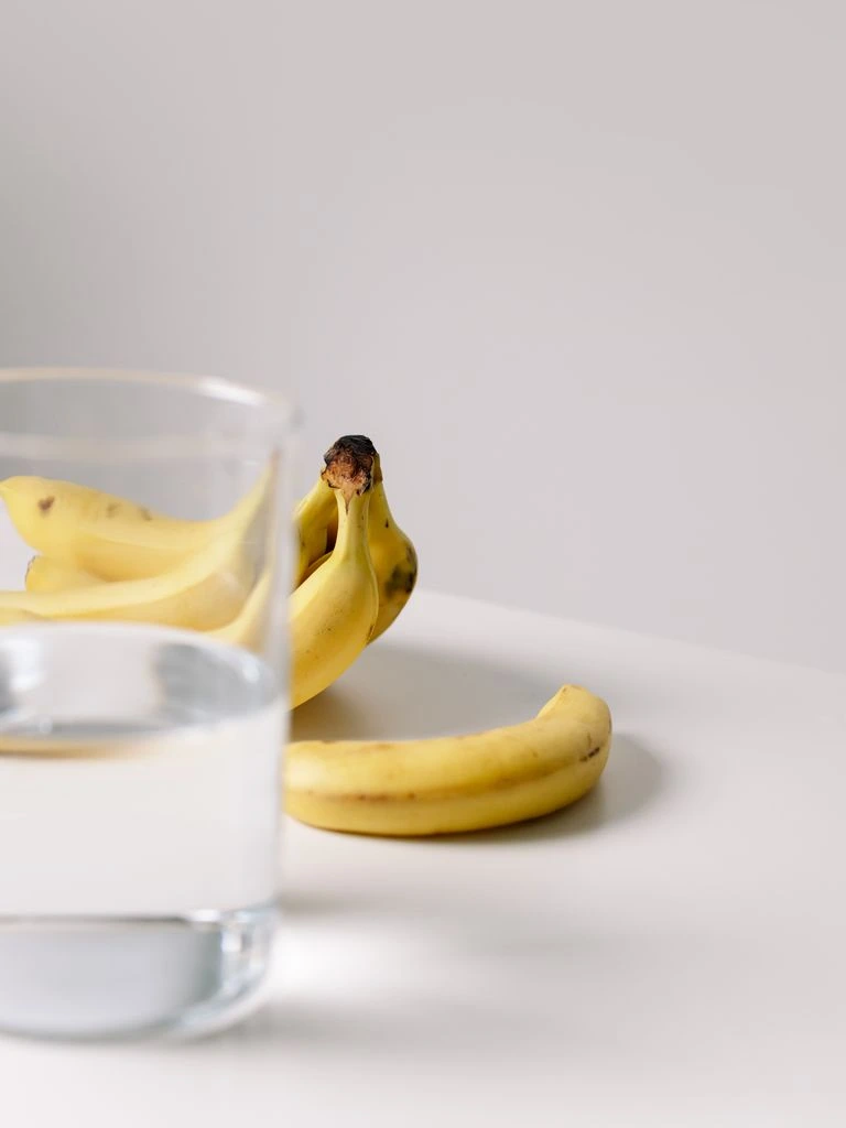 Batido vegano de plátano y avena con nibs de cacao en vaso alto sobre mármol.